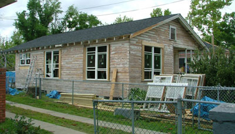 The shotgun style building has a wood exterior.